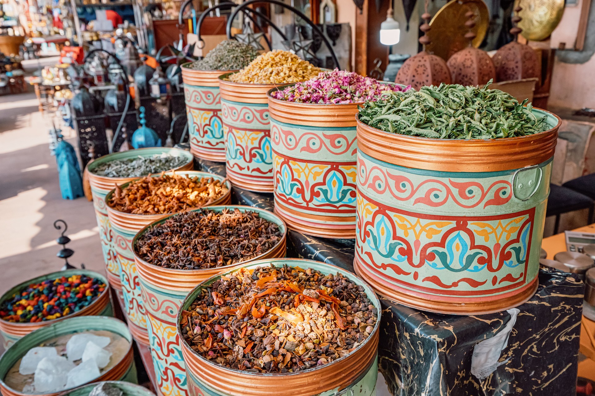 Traditional metal containers overflowing with colorful spices creating a vibrant display in a bustling Marrakech market