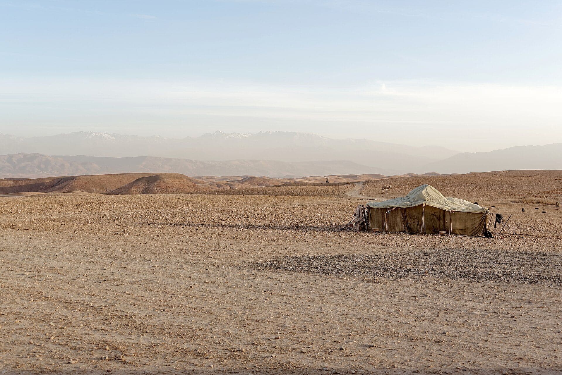 Berbertent in het stenige landschap van de Agafay-woestijn met de Atlas op de achtergrond