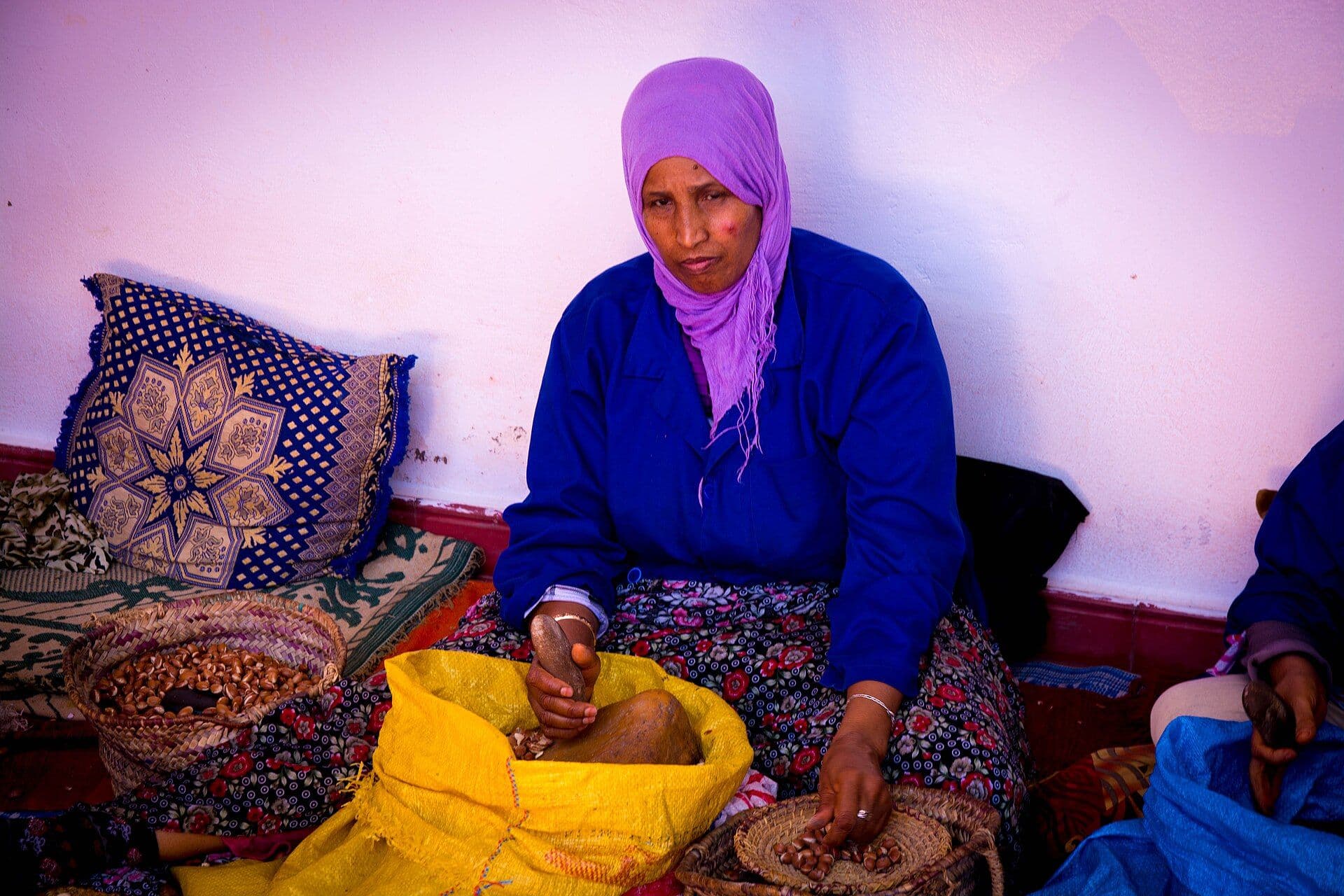 Woman in an argan oil cooperative cracking argan nuts by hand