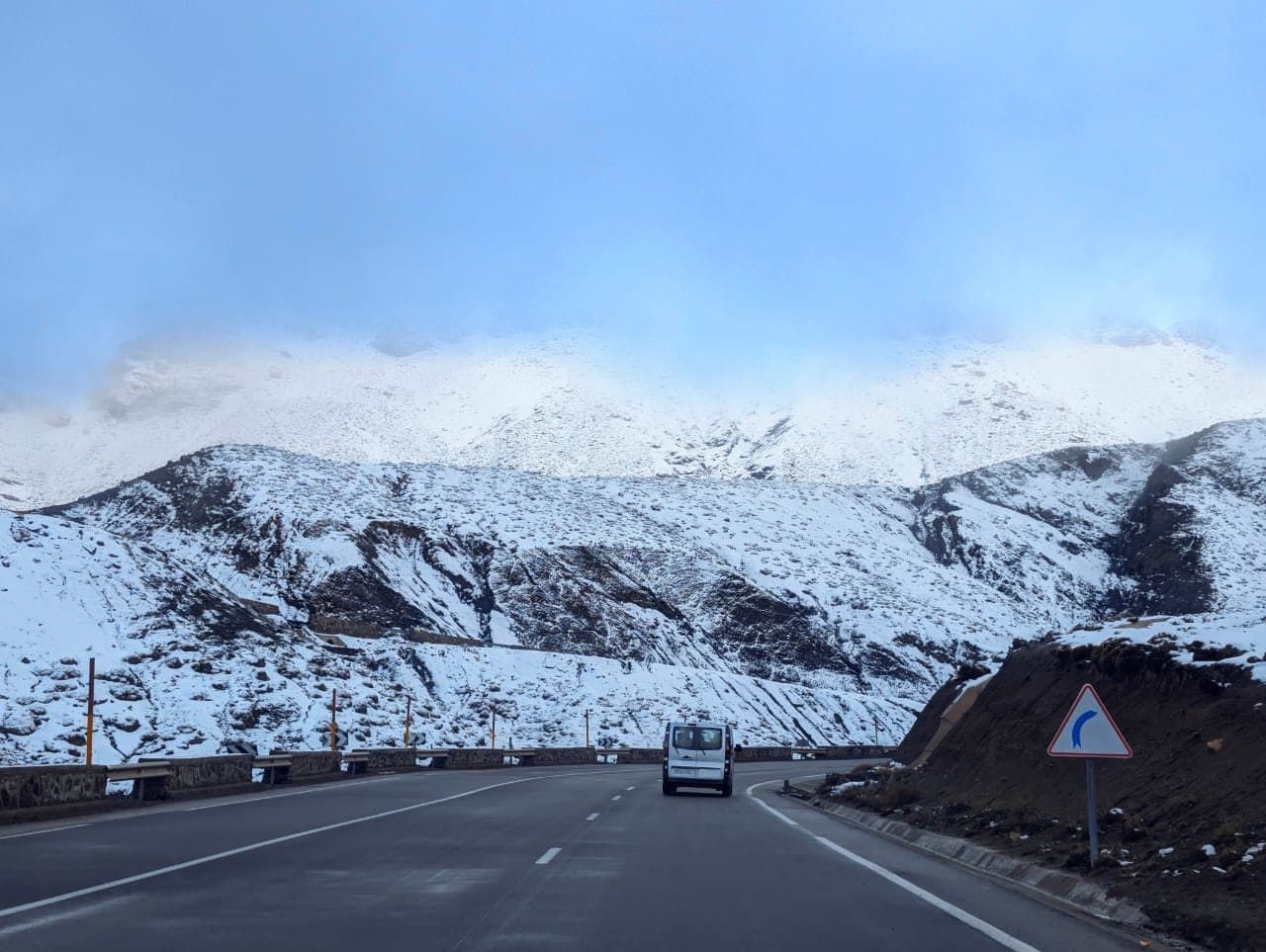 Auto's op de weg door de Hoge Atlas, met besneeuwde bergen aan weerszijden