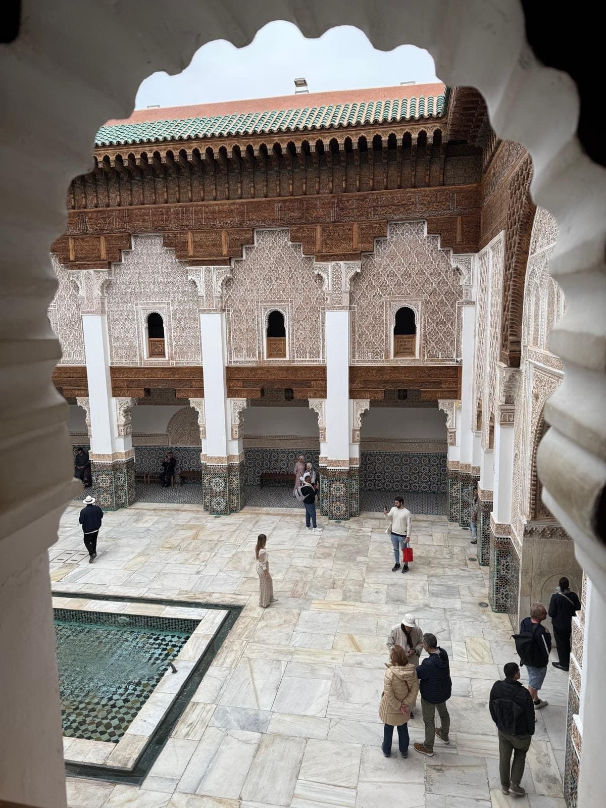 De binnenplaats van de Ben Youssef-madrasa in Marrakesh, gezien door een raam met bogen