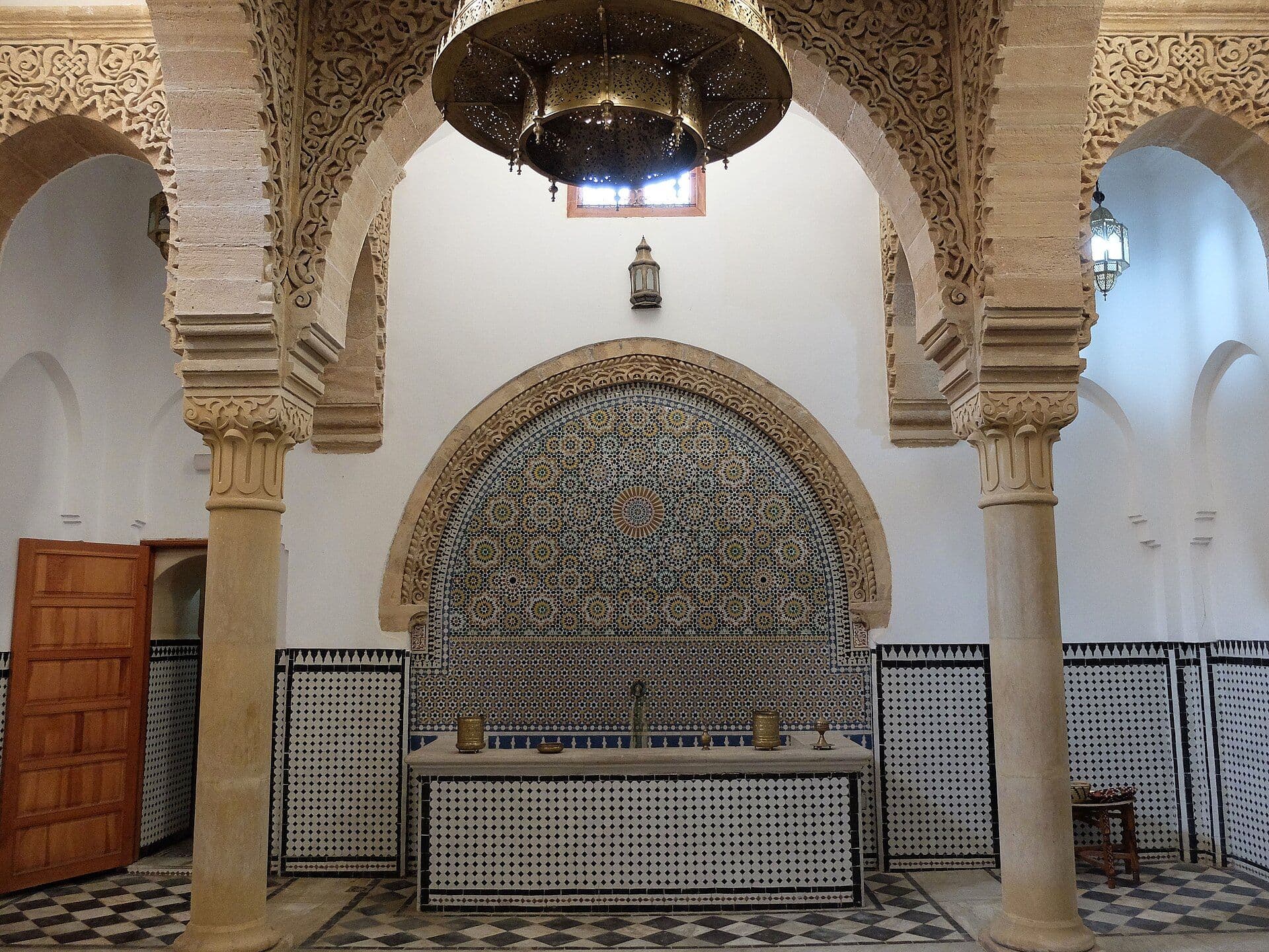 Interior of a traditional hammam with arches, columns and a zellige fountain