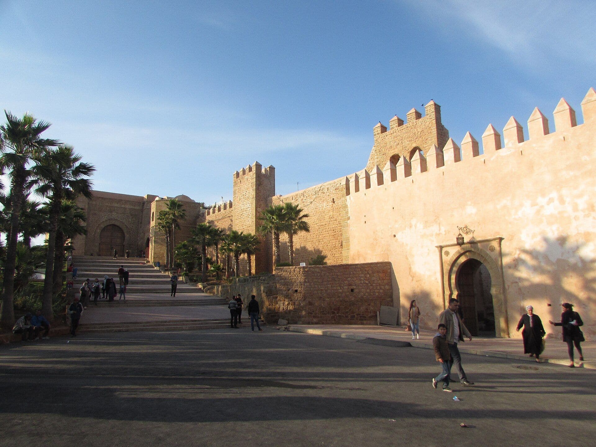 De stadsmuren en de poort van de Kasbah van de Oudayas in Rabat, met palmen ervoor