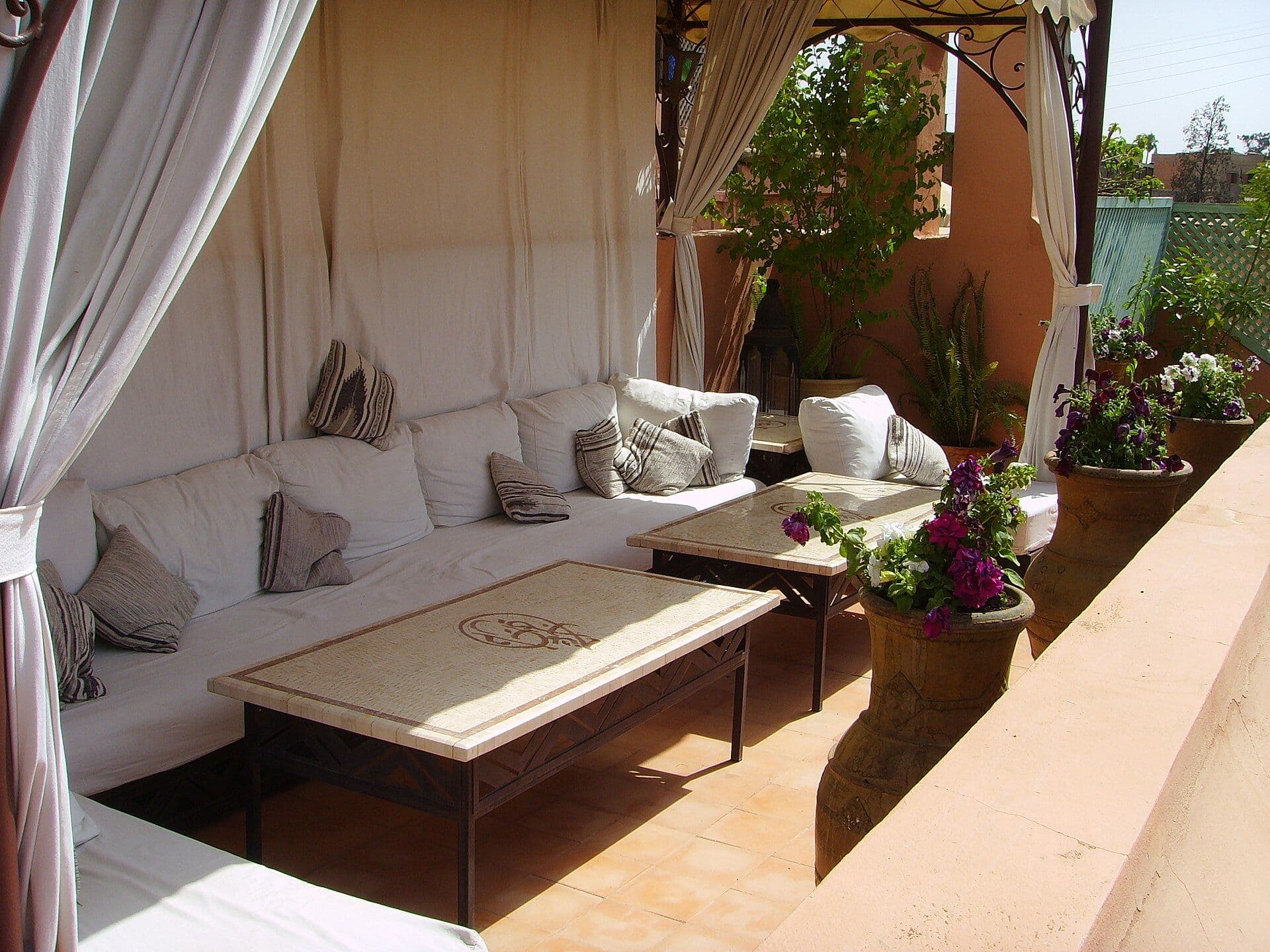 Roof terrace of a riad in Marrakesh with white cushions and flowers