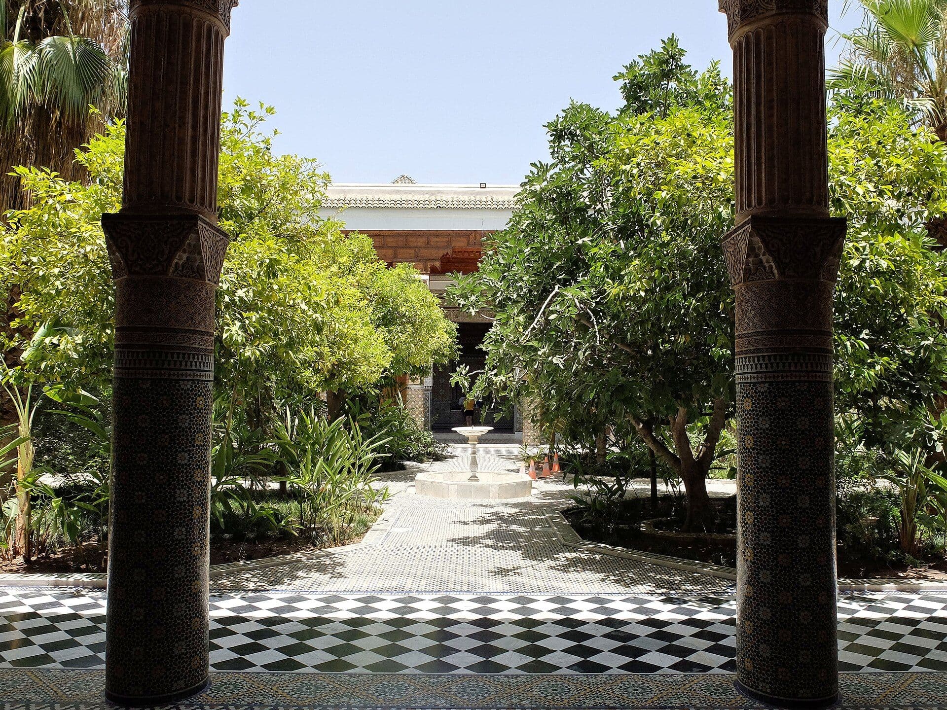 Schaduwrijke binnentuin van een riad in Marrakesh met sinaasappelbomen en zwart-witte tegels