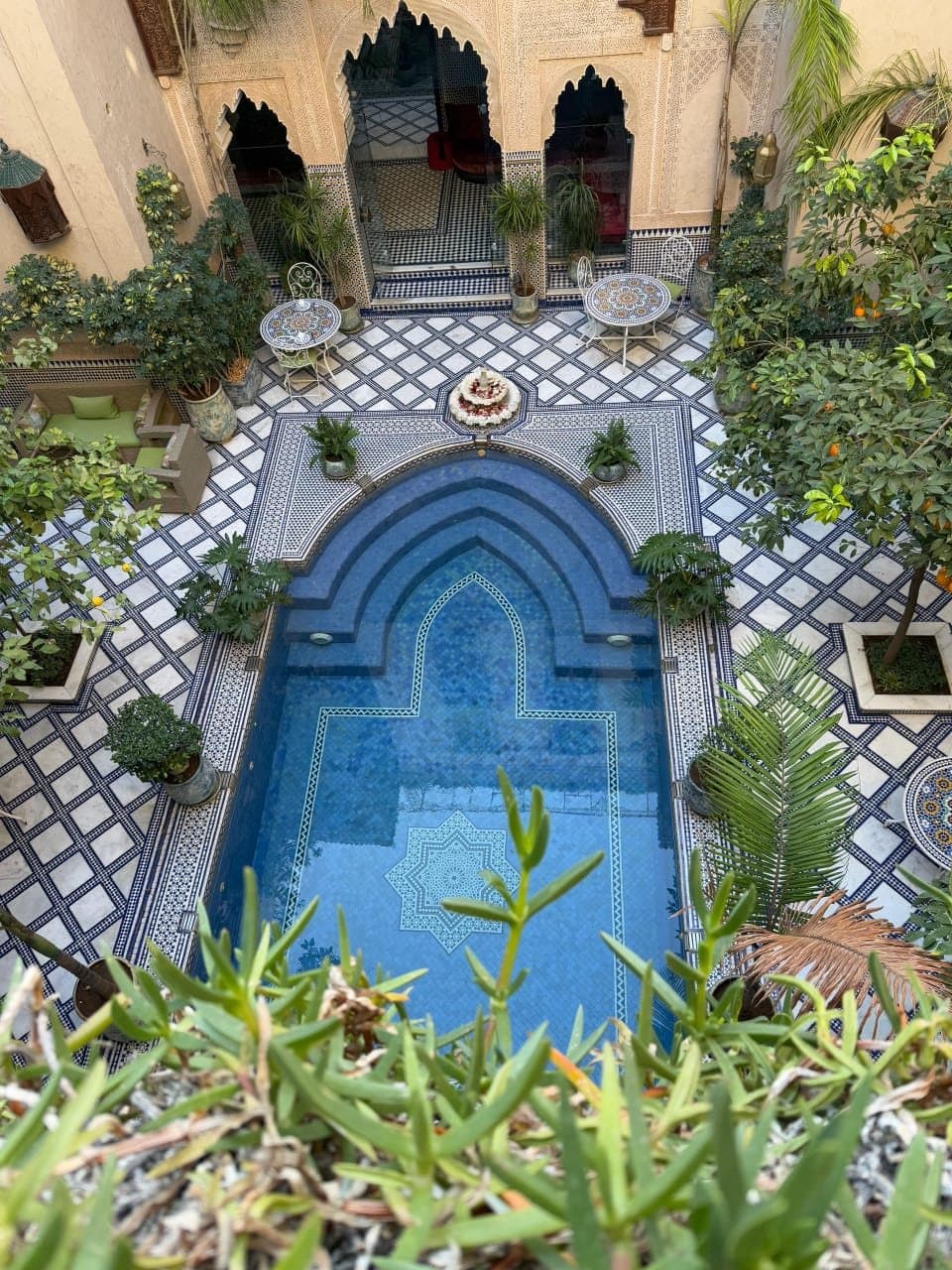 De binnenplaats van een riad met een bassin van zellige, omringd door planten