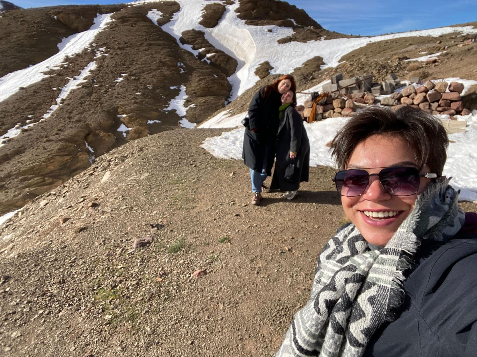 Soukayna (rechts, met zonnebril) maakt een selfie in de besneeuwde Atlas, met twee reizigers op de achtergrond