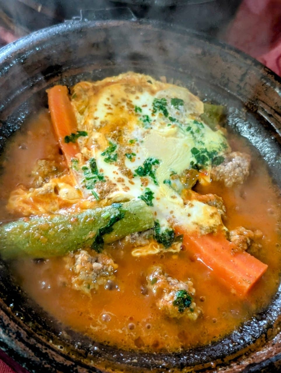 Een tajine met wortel, courgette en ei in een aardewerken schaal