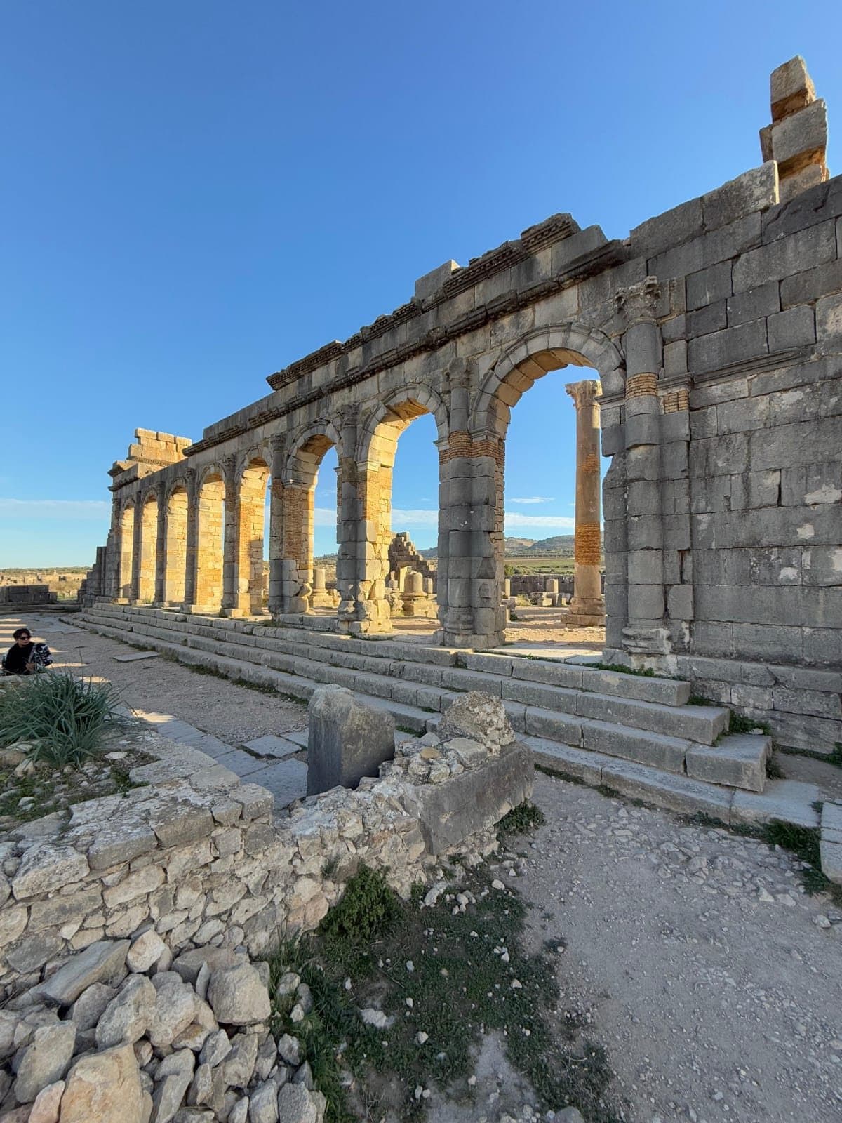 Een rij Romeinse bogen en zuilen in Volubilis onder een blauwe lucht