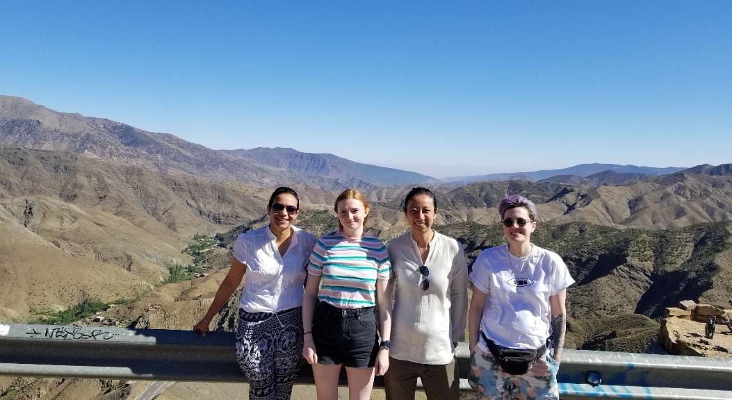 Vier vrouwen bij een vangrail, met de bergen van de Atlas achter hen